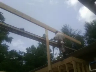 Carpenter setting a ridge beam over a new addition frame — Ice Dam Removal by Roofing Brothers in North